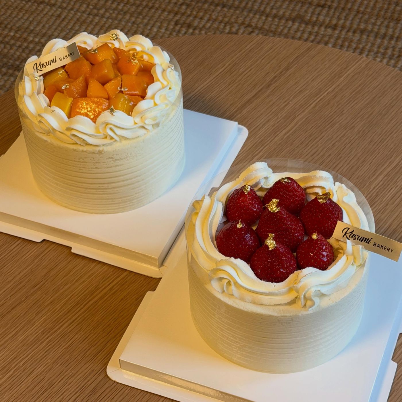 Two fresh cream cakes from Kasumi Bakery, one topped with mango and one with cherries
